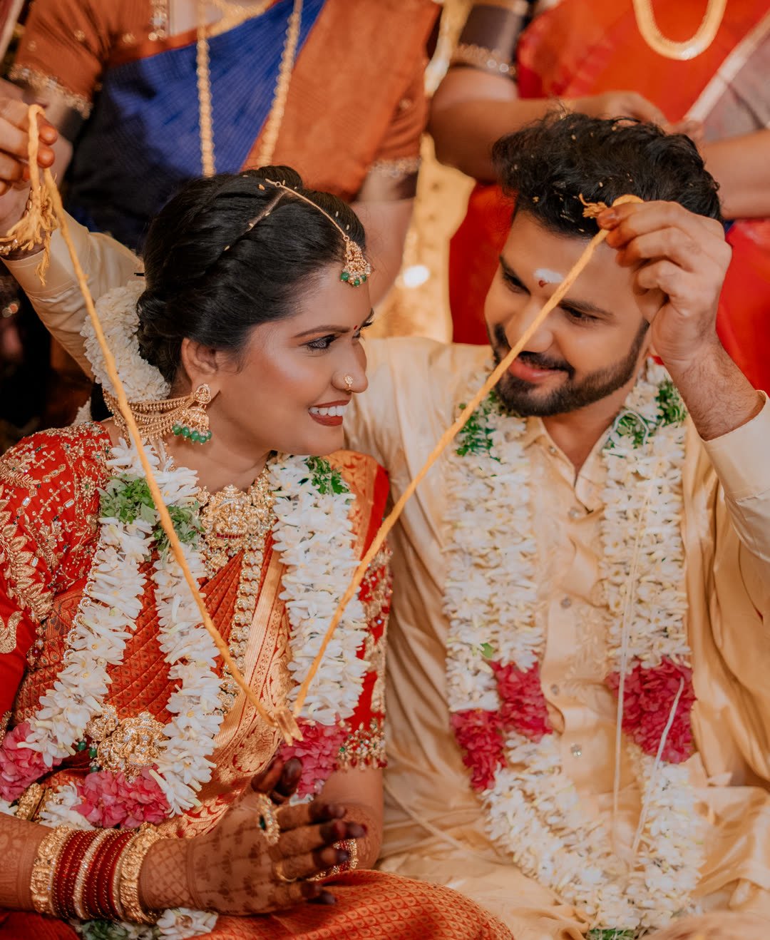Bride and groom holding the mangalsutra thread together during the ceremony